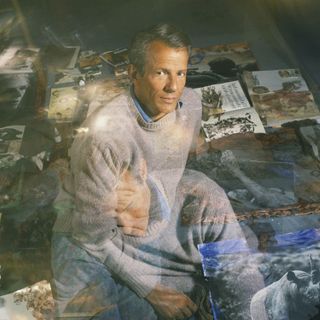 Portrait of a man in grey jumper surrounded by photographs