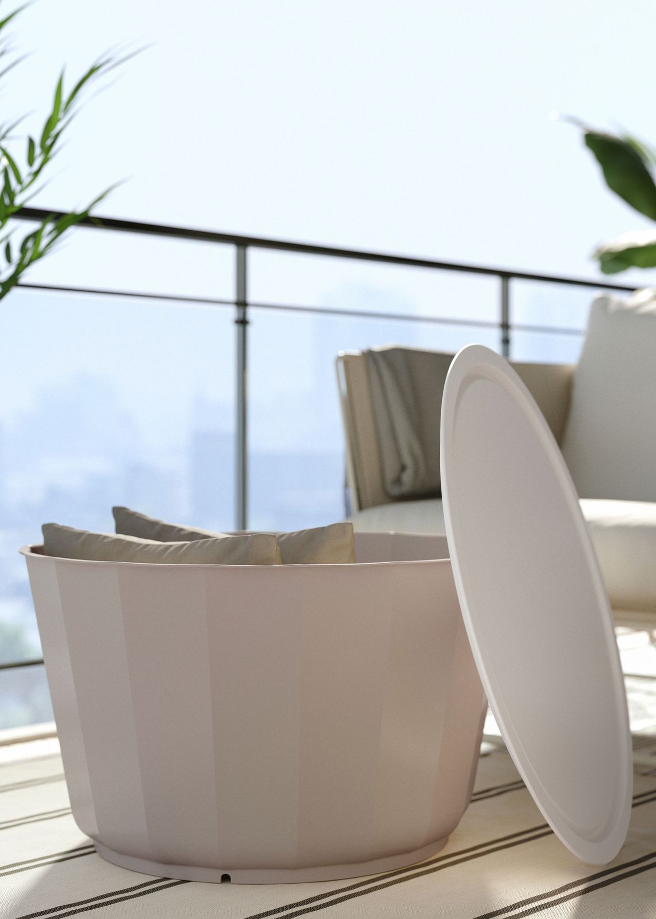 A round coffee beige coffee table with the lid off and propped on the side to reveal two beige cushions within it next to a beige garden sofa on a balcony on a blue sunny day