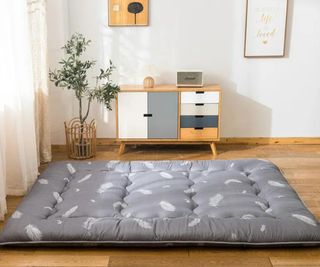 Gray Feathers Futon Floor Mattress on the floor in front of a dresser.