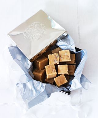 Box of fudge wrapped in blue tissue paper and foil on white table