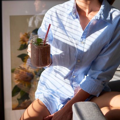 A woman drinking a smoothie in the sunlight