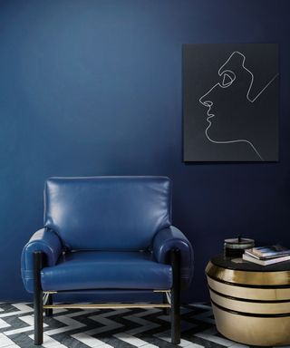 A navy blue room with a blue chair and gold table