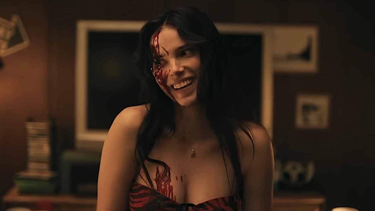 Inde Navarrette as Nikki laughs with blood on her face in Obsession.