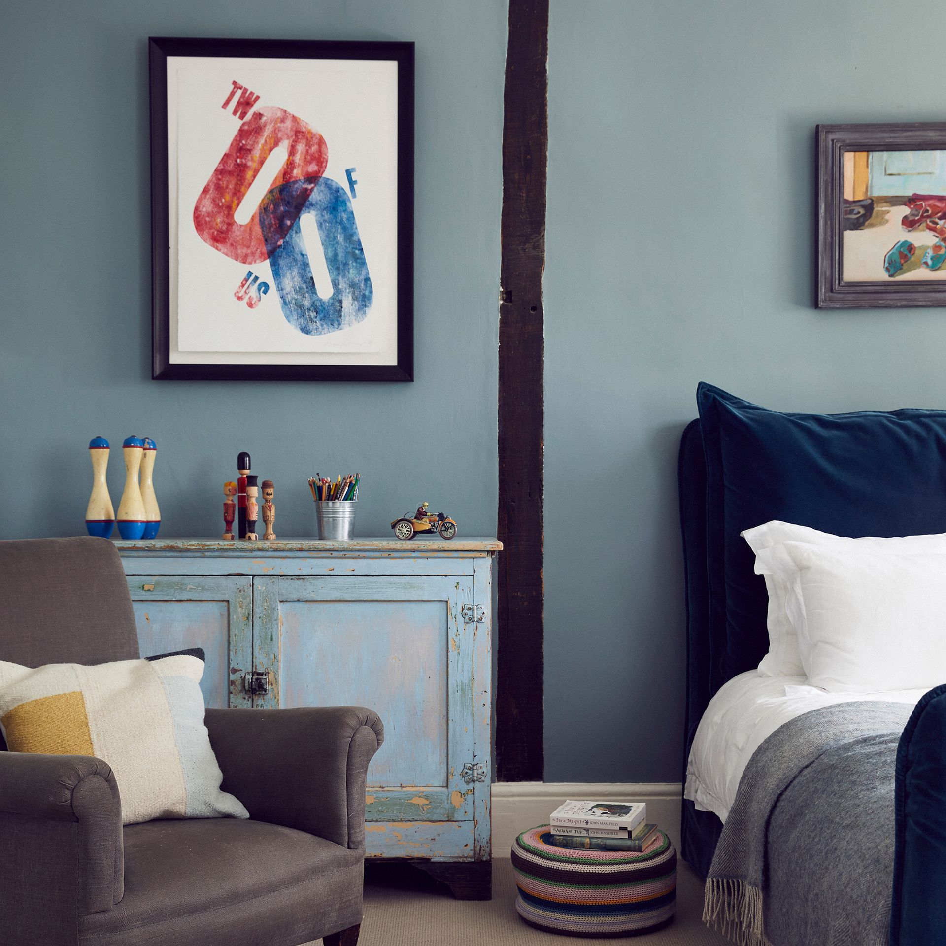 Bedroom with armchair, artwork and vintage sideboard