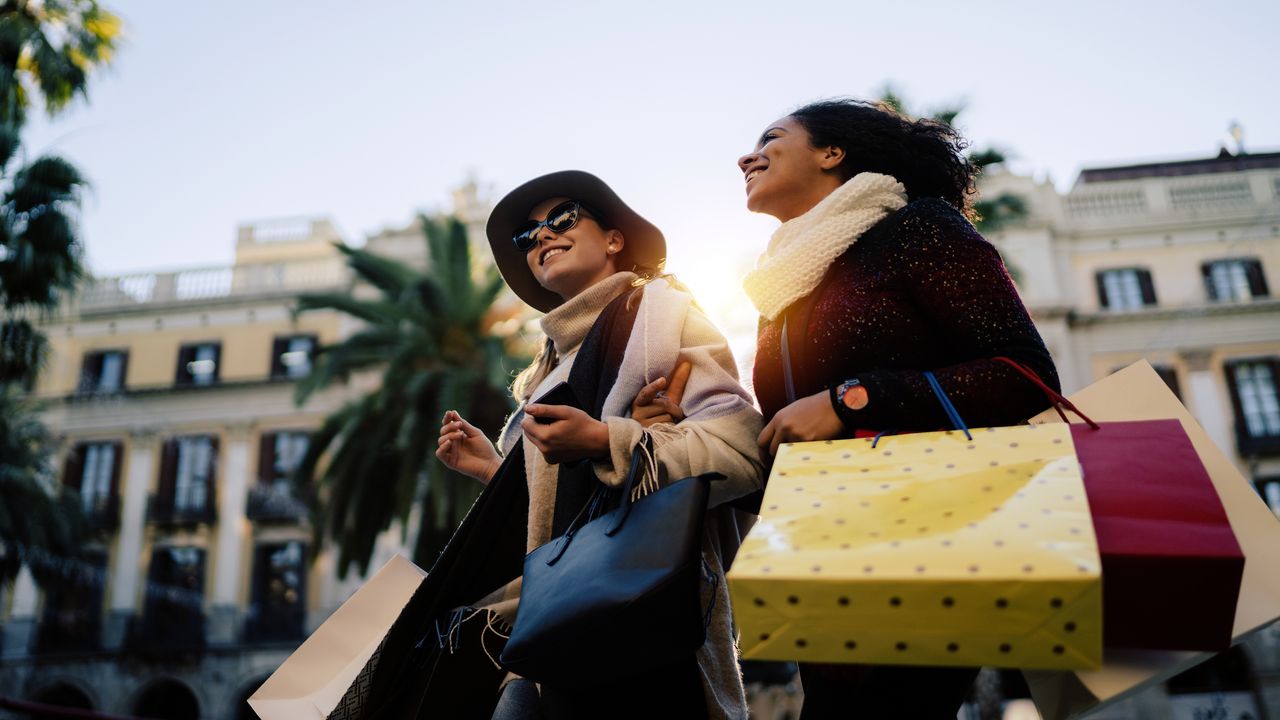 two women with shopping bags walking outside