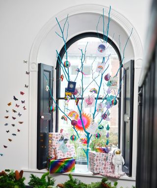 fun alternative Christmas tree idea with sprayed branch in window and colourful diversity inspired decorations