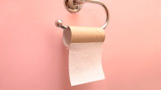 A roll of toilet paper hanging on a holder with only one square left