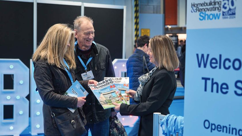 A couple talking to an exhibitor, holding copies of Homebuilding &amp; Renovating magazine, at a Homebuilding &amp; Renovating Show