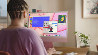 Woman sitting at desk using pink iMac