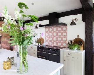 A white kitchen with a pink patterned tile backsplash