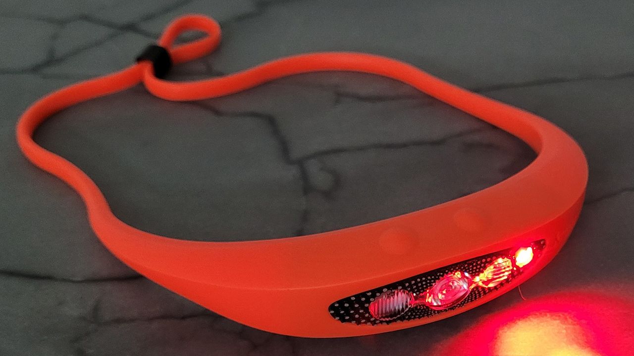 Knog Bilby 400 headlamp sat on a table with the red light illuminated.