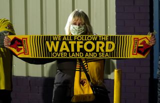 A Watford fan poses for a photo outside the ground despite the postponement