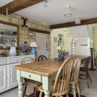 dining room with wooden table and stone wall and wooden beams