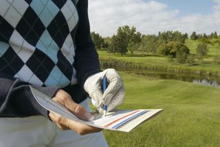 Golfer filling in scorecard GettyImages-522917188