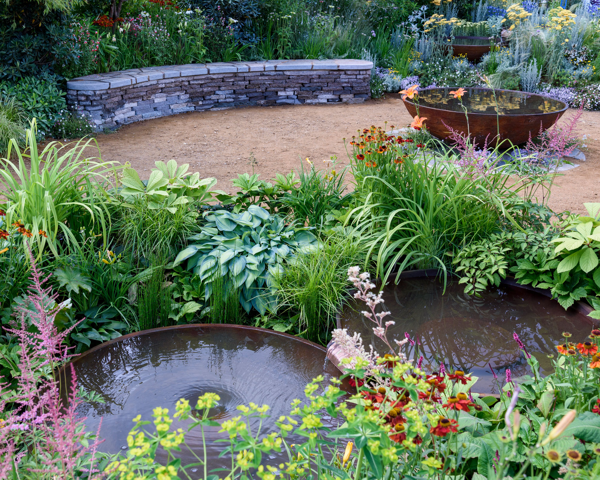 double corten steel bowl pond feature in gravel garden with marginal planting, stone bench and additional corten steel freestanding pond feature