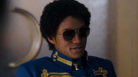 Jafaar Jackson as Michael Jackson, wearing sunglass and blue military-style top