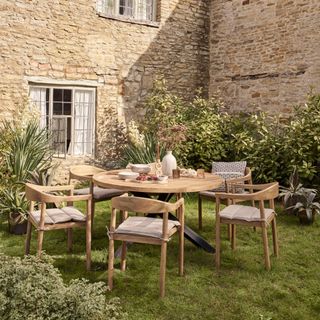 Garden with wooden table and chairs with cushions