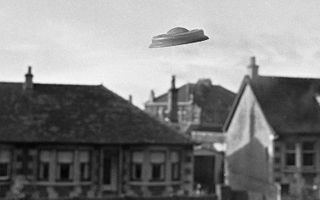 A fake UFO hovers over a house in a black and white image
