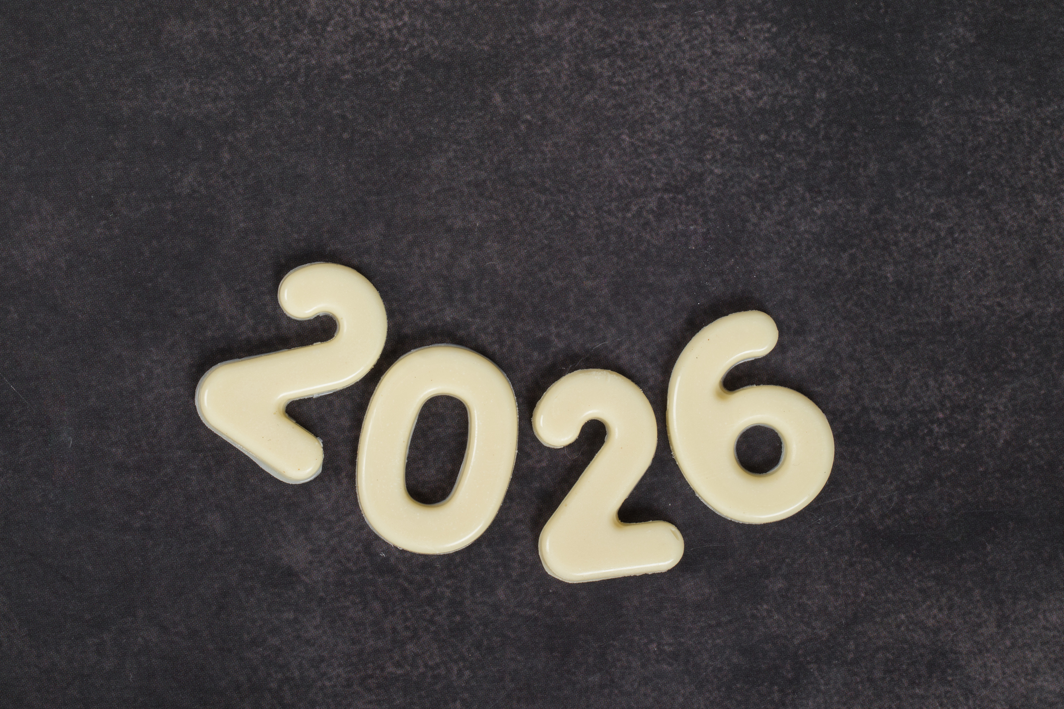 New Year 2026. White chocolate numbers. Dark gray background. Top view