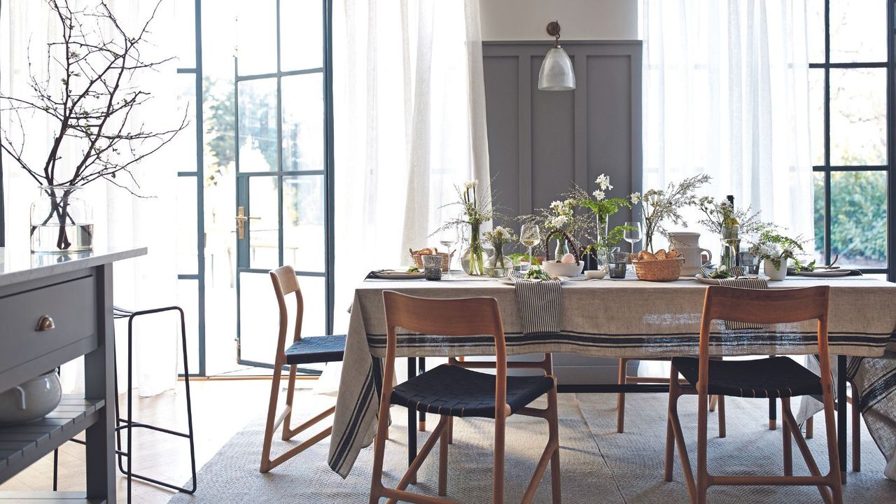 Grey and white dining room with retro chairs and table with tablecloth laid with spring flower displays