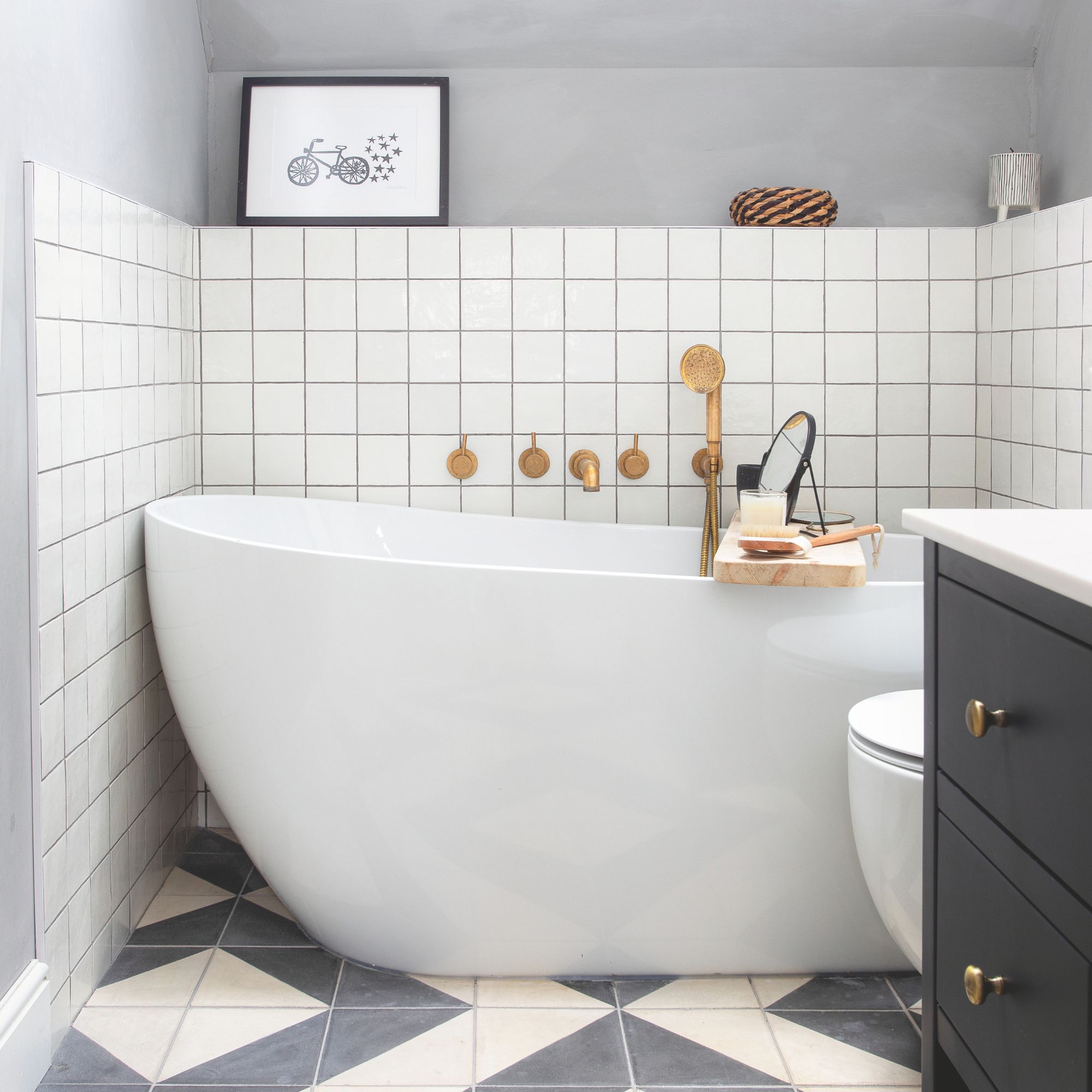 White tiled bathroom with freestanding white tub and black and white floor tiles