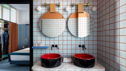 a hotel bathroom with blue tiles and orange grouting