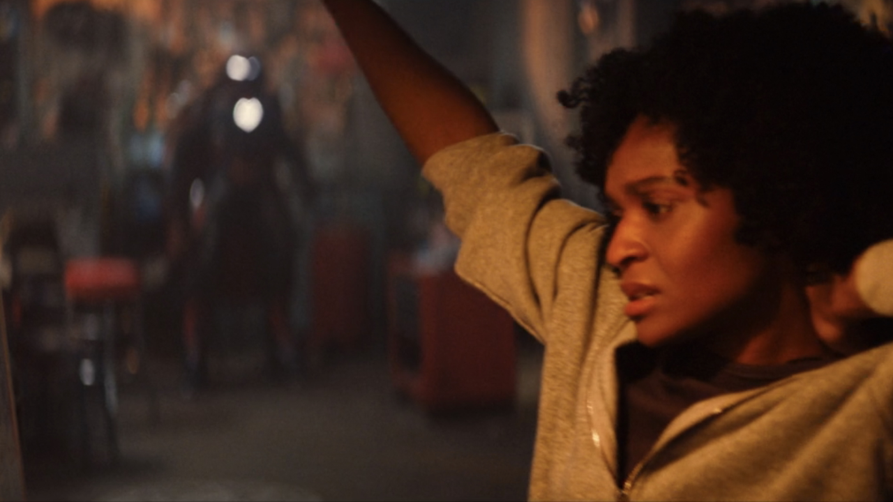 Riri stretching with her Hood-covered Ironheart armor in the background in Ironheart season finale