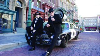 The Blues Brothers pose on their patrol car on a street at Universal Studios Florida.
