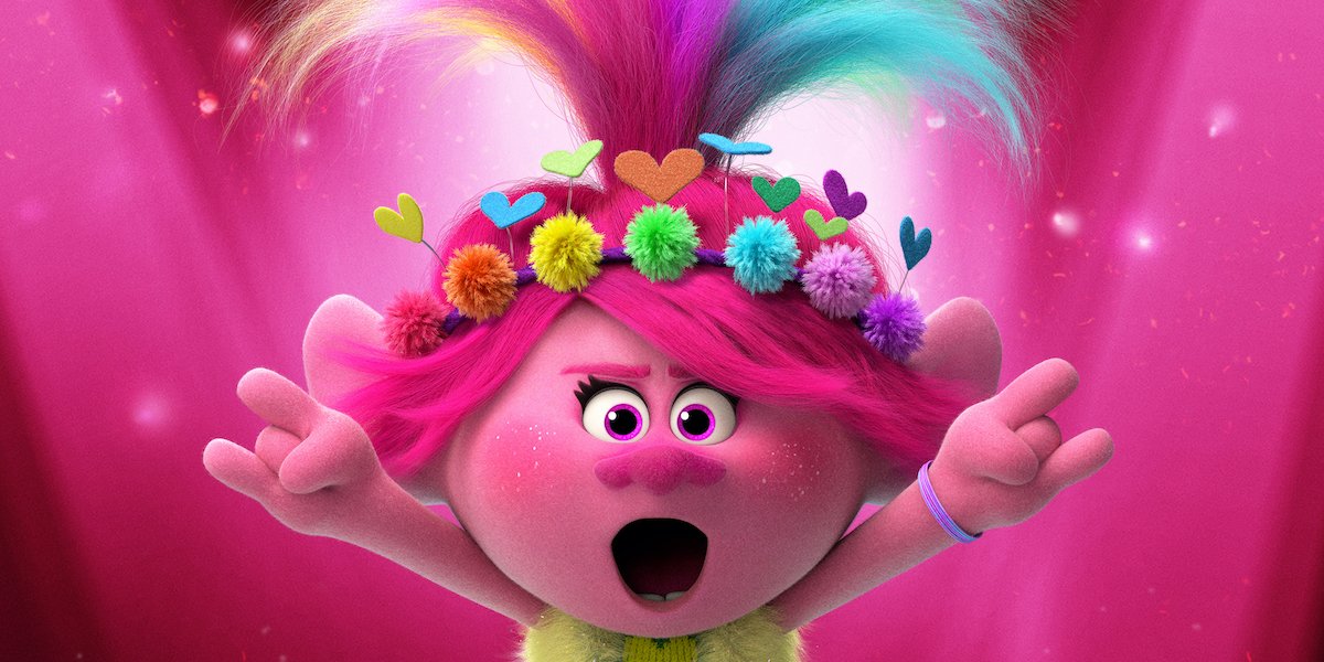 A troll wearing a heart and flower headband rocks out on stage in Trolls World Tour.