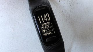 Nærbillede af skærmen af en sort Garmin Vivosmart, som viser klokkeslæt, dato, skridt, puls og batteriniveau