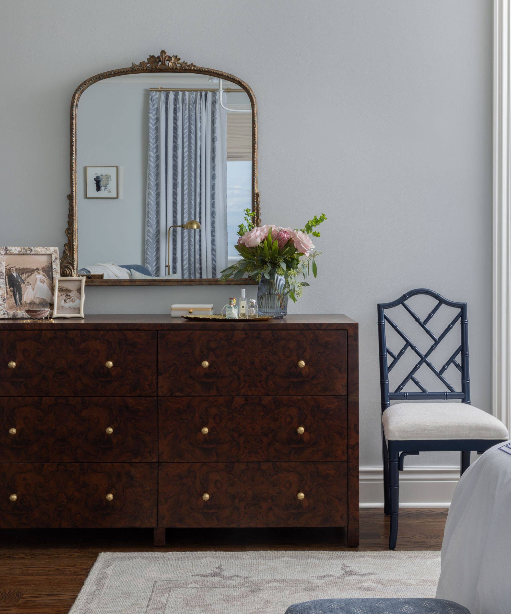 bedroom with blue-gray walls, a dark dresser and a traditional mirror on the wall