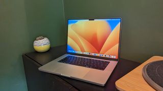 MacBook Pro 16-inch (2023) on wooden desk with green background