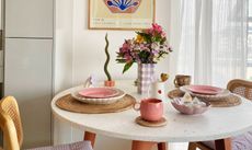 Pink dining room space with wooden chairs and colorful abstract print on the wall