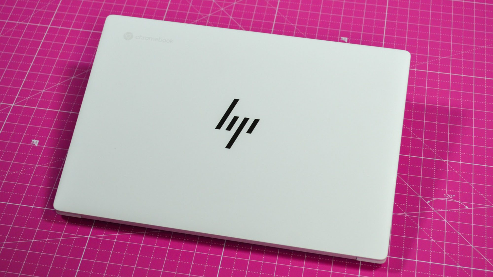 An HP Dragonfly Pro Chromebook on a ruled pink desk mat
