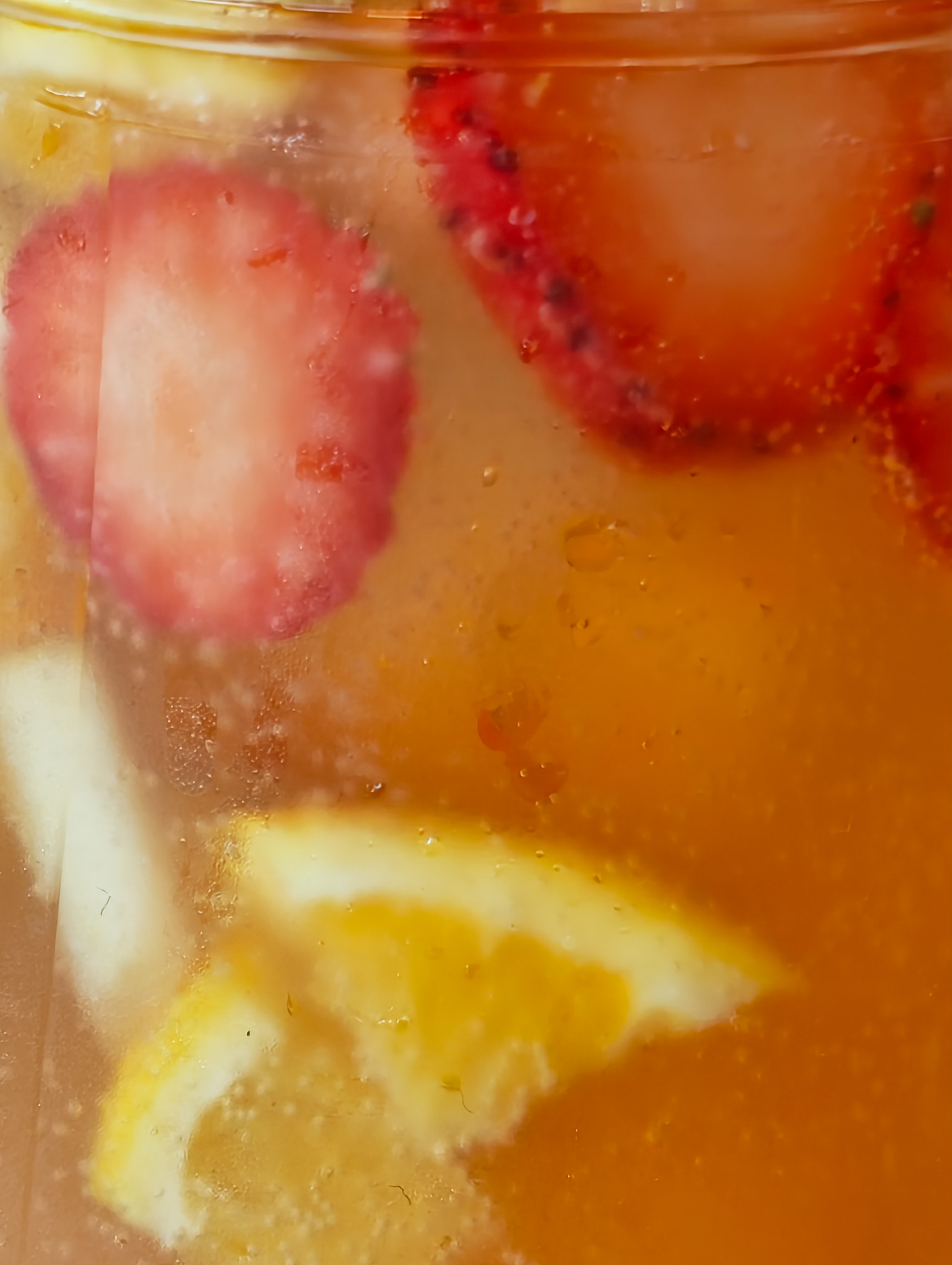 Close-up of a chilled fruit drink with sliced strawberries, citrus, and ice inside a glass, photographed with the Nothing Phone (4a).