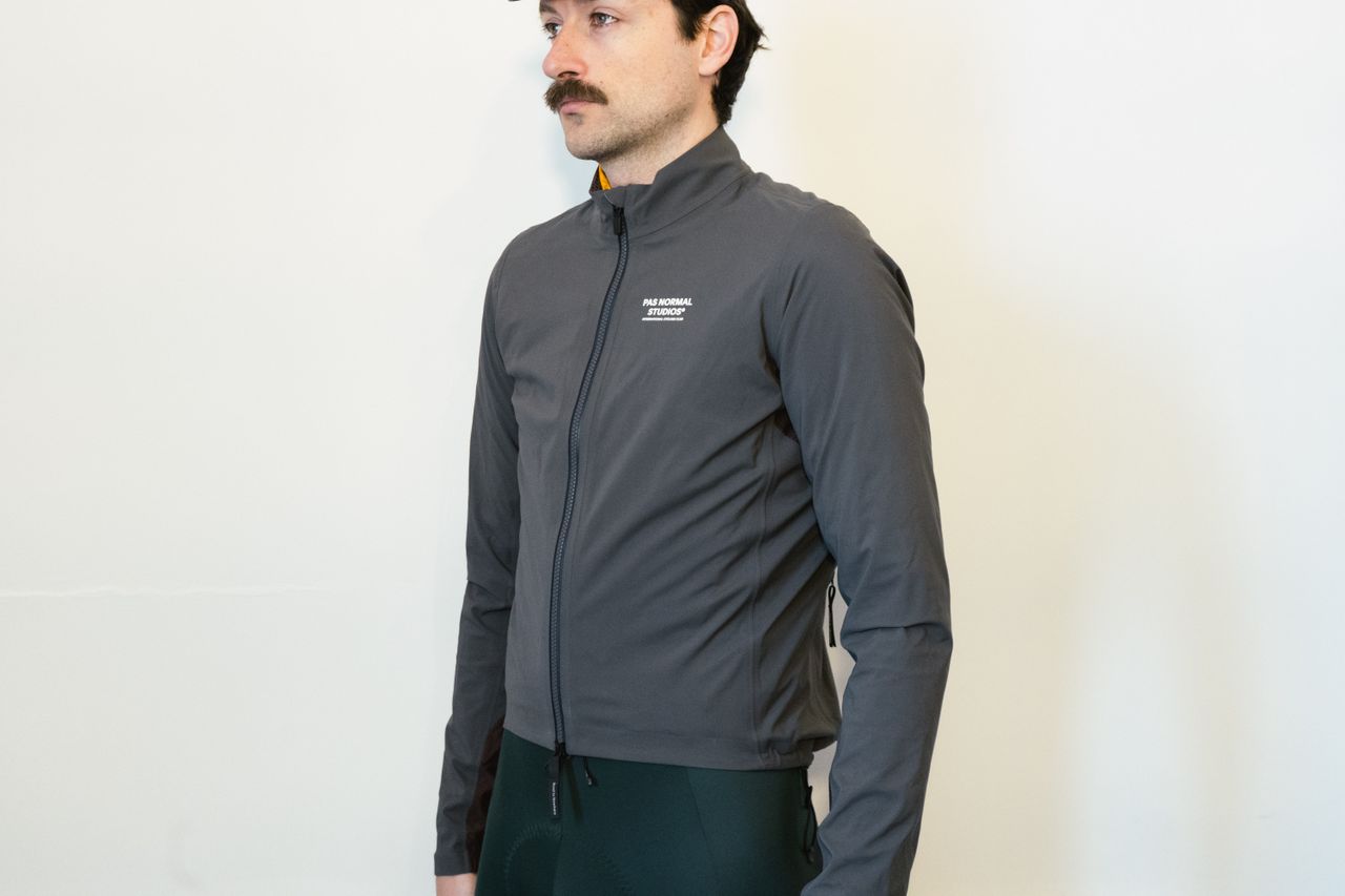 A man in a grey waterproof jacket against a white wall