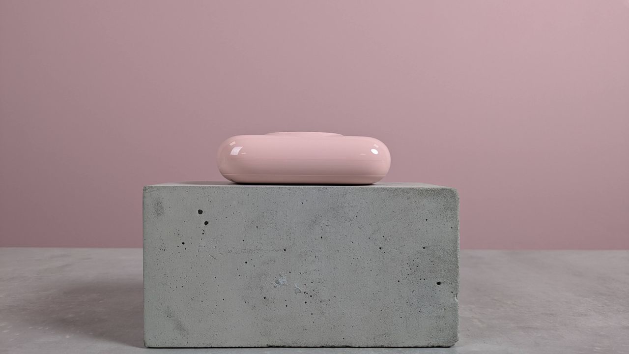 Side view of VRURC T6S power bank on plinth on desk with pink background