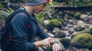Man checking sports watch while hiking in woods
