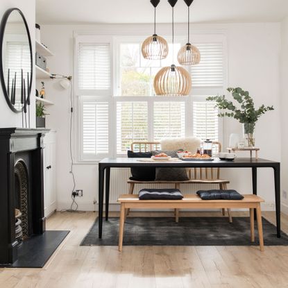 white dining room with black accents and statement rattan ceiling lights