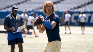 Glen Powell as Chad Powers holding a football in the Disney Plus show Chad Powers 