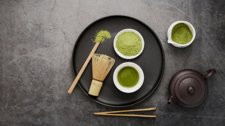 Matcha powder and black teapot on grey slate background