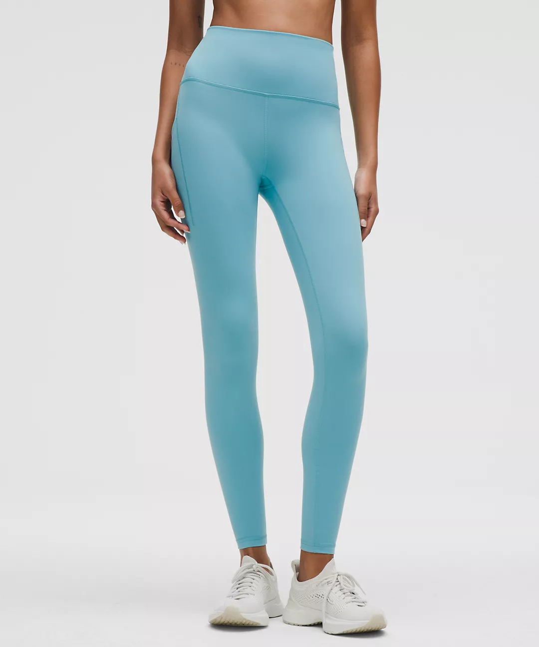 Woman wearing blue leggings against gray background