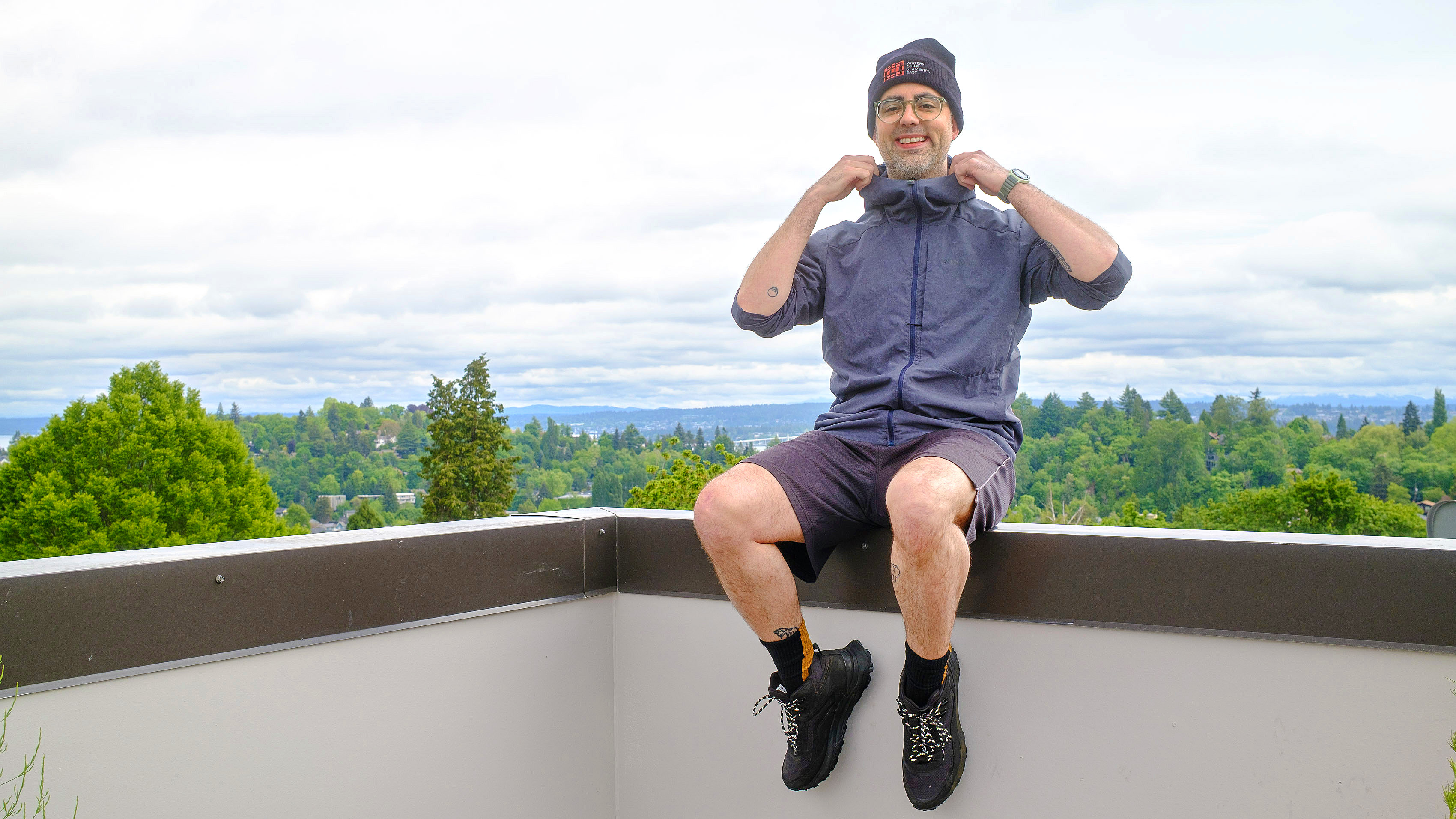Senior writer Dan Bracaglia wearing the Patagonia Nano-Air Ultralight in grey/blue on the roof of his home in Seattle, Washington with trees and overcast skies in the distance