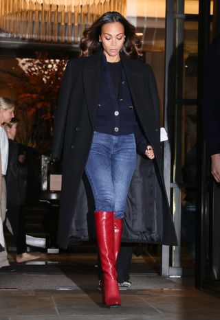 Zoe Saldana wears skinny jeans with knee-high red boots and a black coat