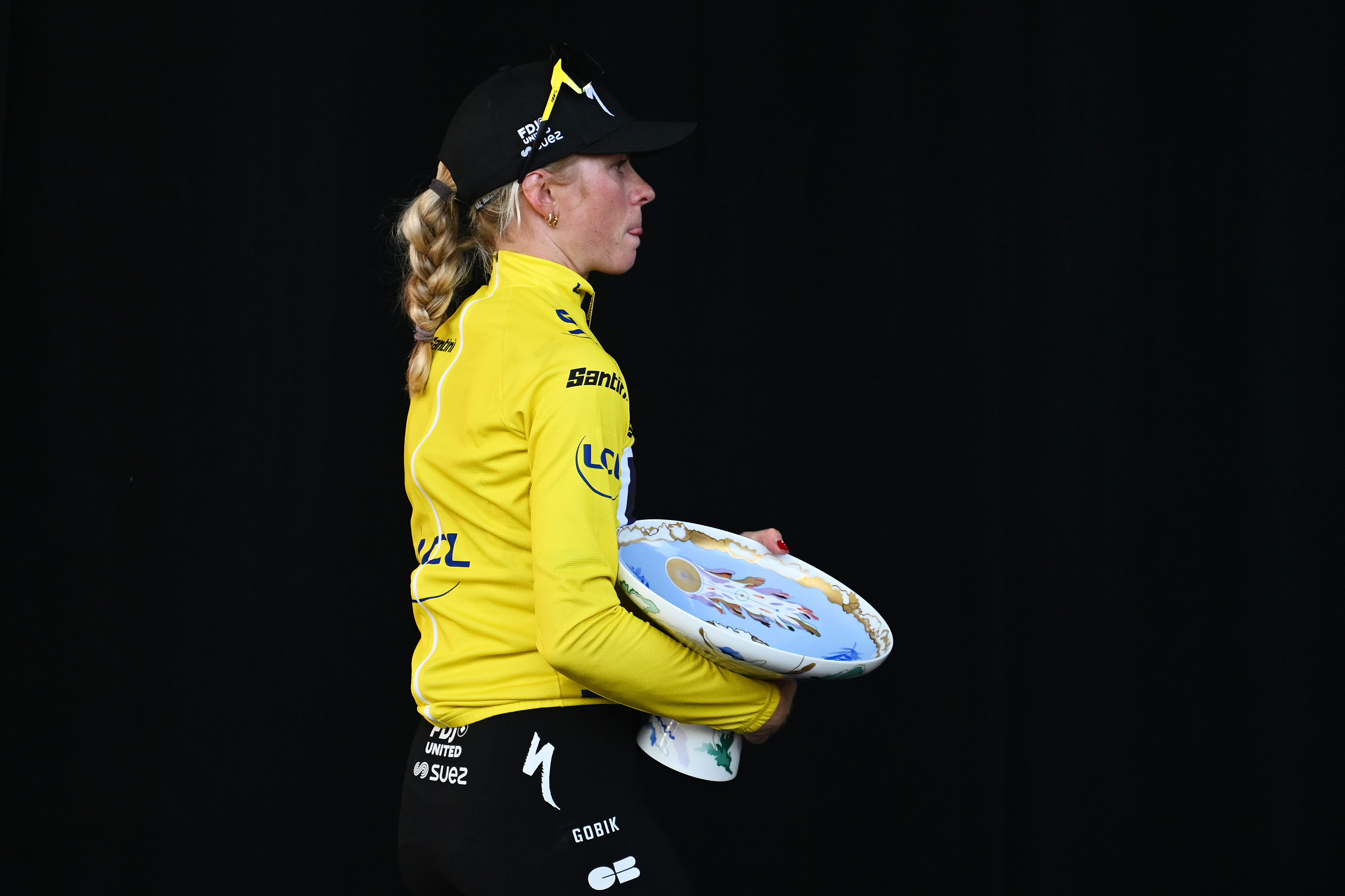 Demi Vollering stands on the Tour de France Femmes podium in the yellow jersey with the winner's trophy