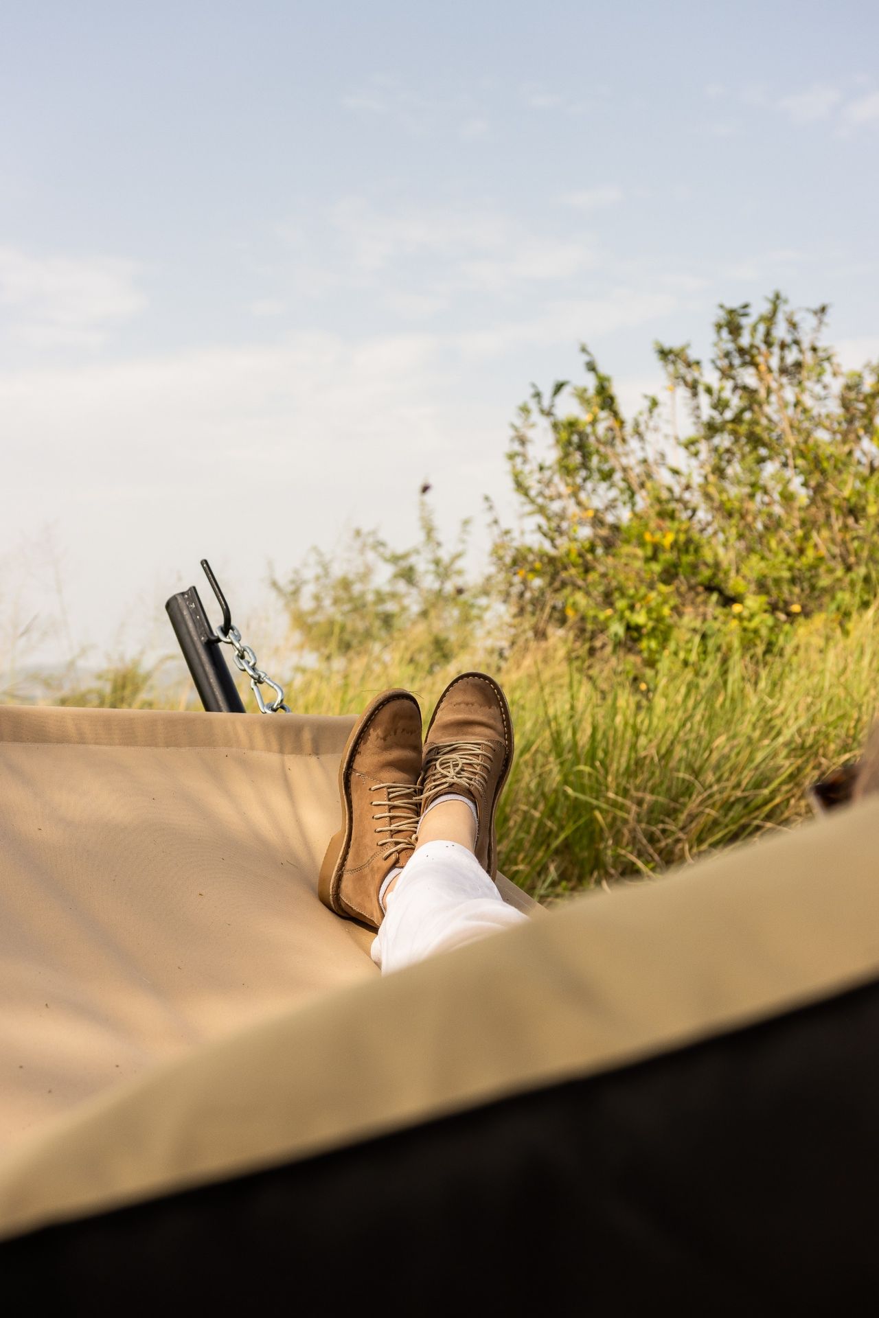 A person's ankles and feet in a hammock