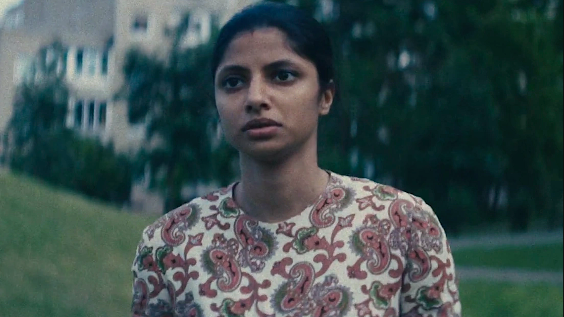 a young woman in a patterned dress on a lawn
