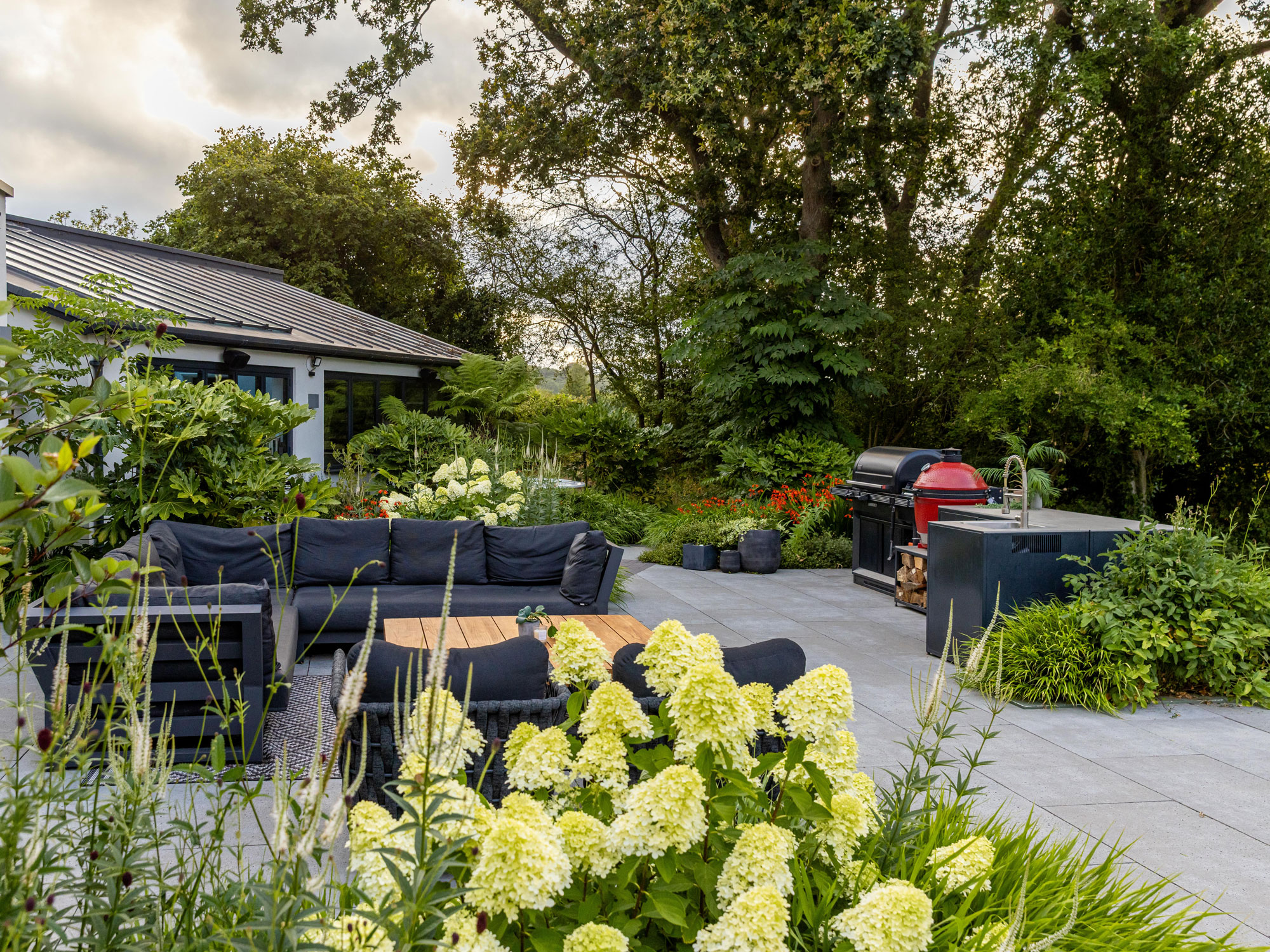 patio with planting islands, garden furniture set up and outdoor kitchen