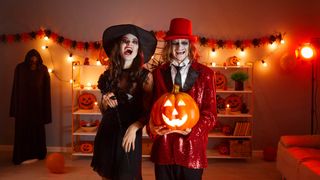 Two people in Halloween costumes in a Halloween-themed room