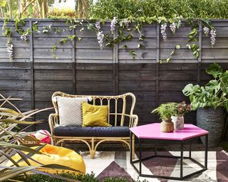 Two tone grey painted fence with seating area and pink side table
